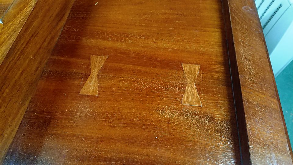 Two inlaid butterfly keys stabilising a split in a polished table top