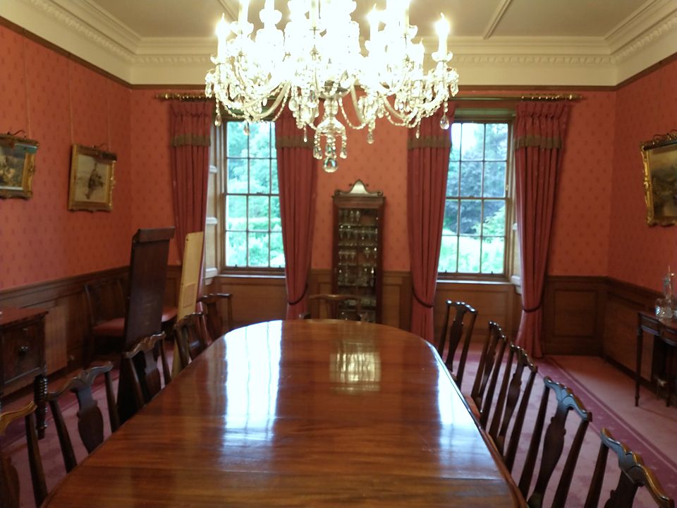 High-gloss polished dining table in a red-walled dining room under a crystal chandelier