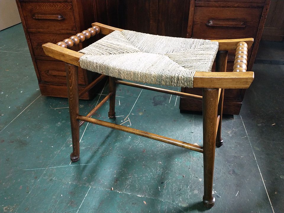 Stool with a new rush seat between bobbin-turned rails