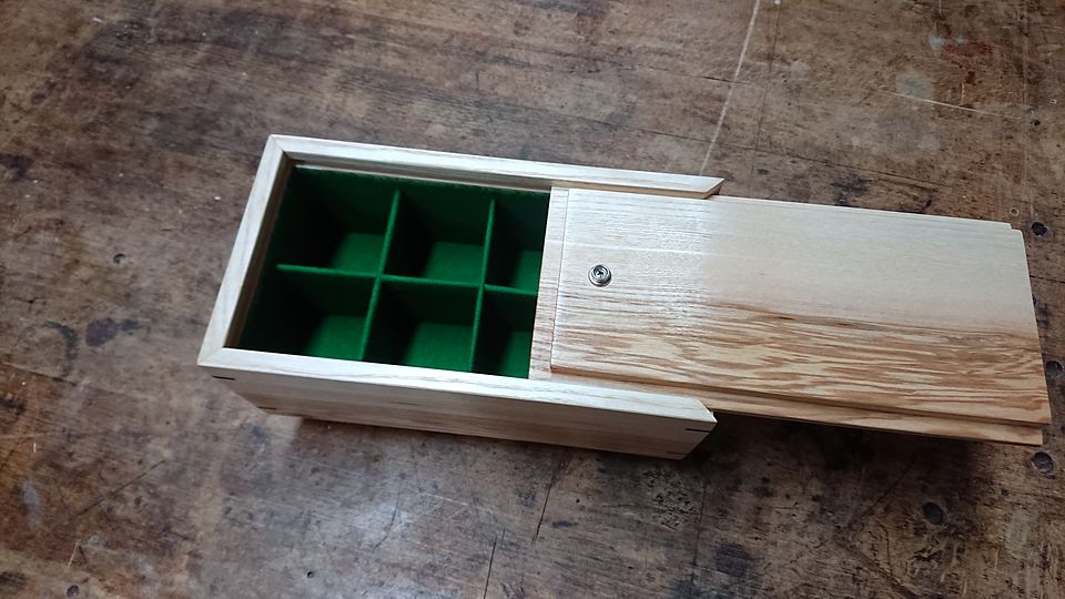 Small box with a sliding lid opened to show green felt-lined compartments